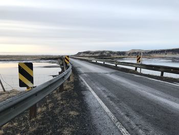 Road by sea against sky during winter