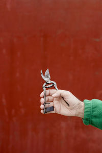 Close-up of hand holding umbrella against wall