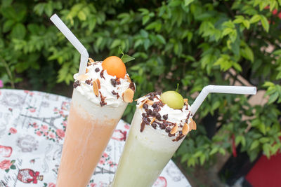 Tilt shot of fresh drinks on table against plants