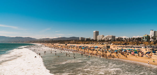 Panoramic view of beach and buildings against blue sky