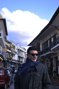 Man wearing warm clothing and sunglasses standing in city