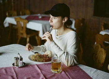 Woman eating food on table in restaurant