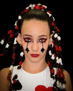 Close-up portrait of young woman against black background