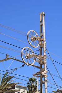 Low angle view of telephone pole against clear blue sky