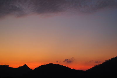 Scenic view of silhouette mountains against orange sky