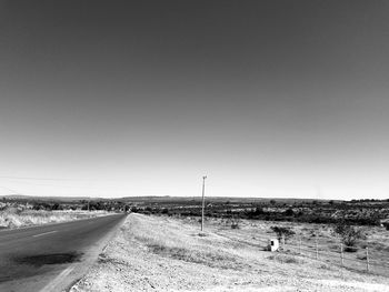 Road amidst field against clear sky