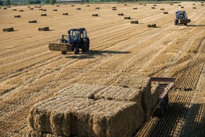 High angle view of hay bales and agricultural machinery on field