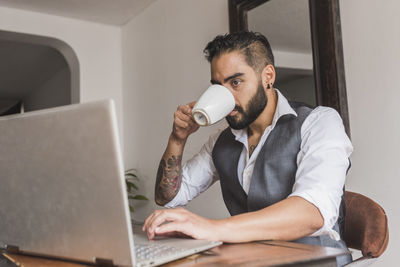 Handsome man dressed as executive drinking coffee and working