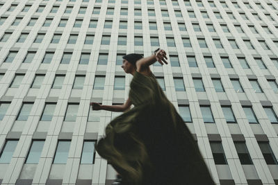 A woman runs under the windows of a building