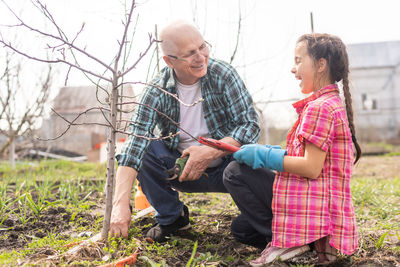 Happy grandfather with granddaughter gardening outdoors