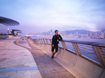 Man on footpath against sky in hong kong city