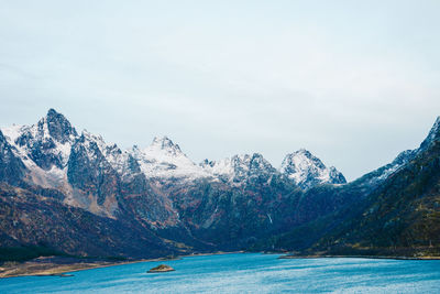 Scenic view of lake by snowcapped mountains against sky