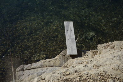 High angle view of wooden plank on rocky shore