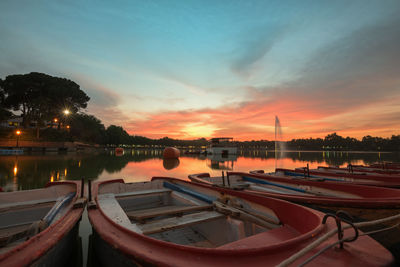 Boats moored in river at sunset