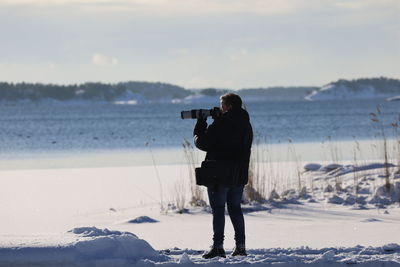 Woman photographing on snow covered land