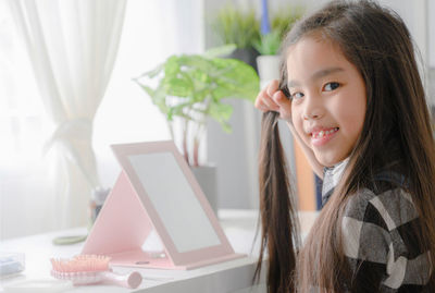 Portrait of smiling girl using laptop on table