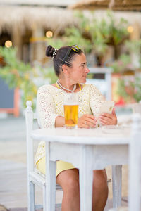 Portrait of woman drinking beer at beach cafe