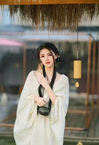 Portrait of young woman standing against wall