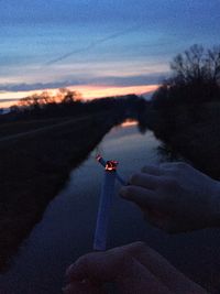 Person holding umbrella against sky at dusk