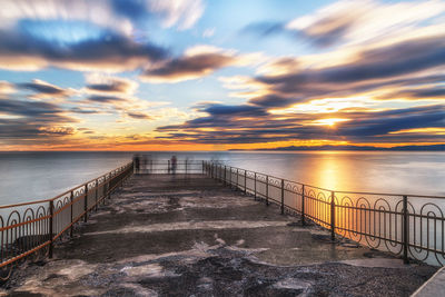 Pier over sea against sky during sunset