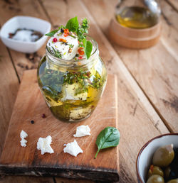 Marinated feta cheese in olive oil, herbs and red pepper flakes on wooden background