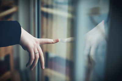 Cropped image of hand touching glass