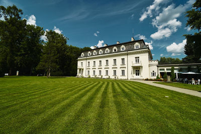 Lawn by building on field against sky