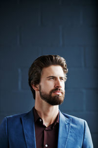 Young man looking away against wall