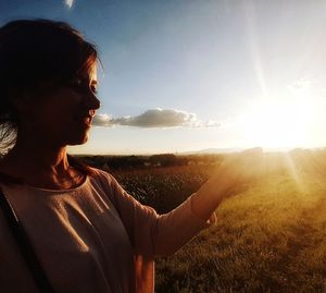 Close-up of woman standing on field against sky during sunset