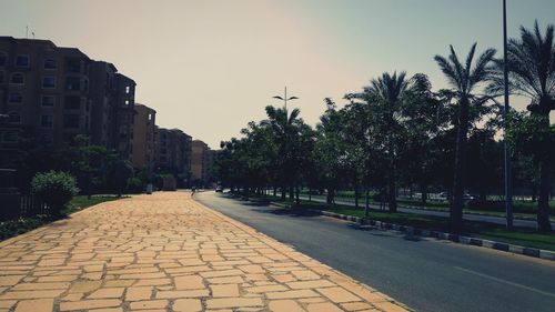 Street amidst trees and buildings against sky