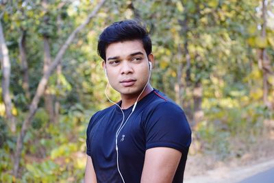 Portrait of young man standing against trees