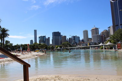 Modern cityscape by river against sky