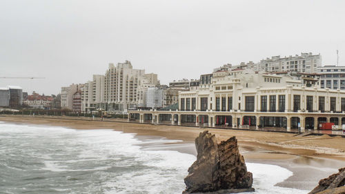 Buildings by sea against clear sky during winter