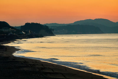 Scenic view of beach against orange sky