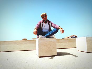 Full length of man sitting against clear sky