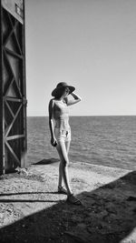 Woman wearing hat while standing against sea