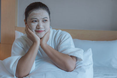 Portrait of woman sitting on bed at home