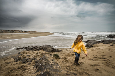 Girl in storm on windswept beach hair blowing in face