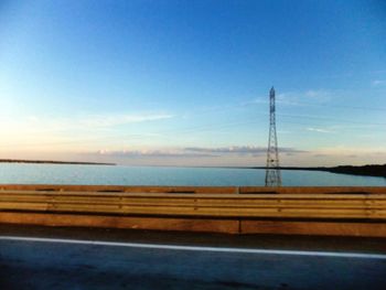 Road by sea against clear blue sky