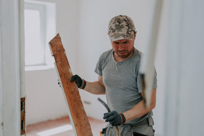 A man working with a crowbar in a doorway.