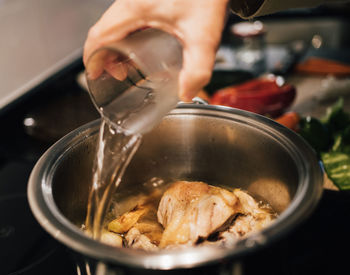 Woman hand adding water on a cooking pot. preparing chicken soup. food chef cook concepts