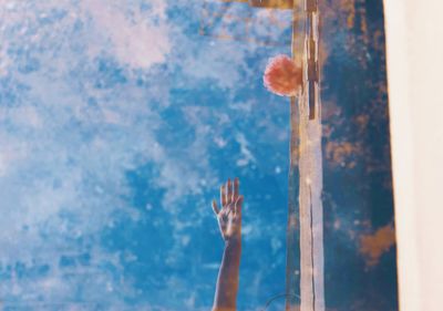 Close-up of hand against blue sky