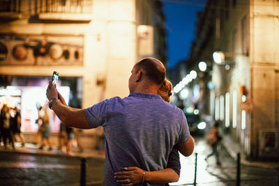 Rear view of man standing on street at night