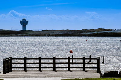 Lighthouse by sea against sky