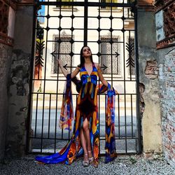 Full length of woman standing against gate of building