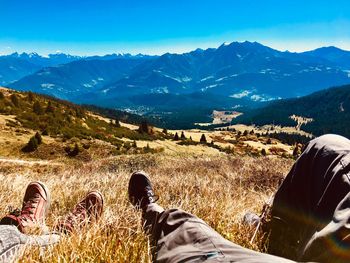 Low section of man standing on mountain against sky