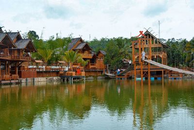 Houses by lake and buildings against sky