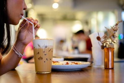 Midsection of woman drinking coffee cup on table