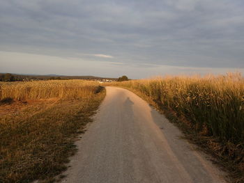 Road amidst field against sky