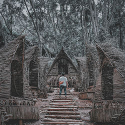 Rear view of man walking on staircase in forest